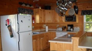 A kitchen with wooden cabinets, a refrigerator, a microwave, and a sink. - Sandy Beach Cottage! (Belgrade)