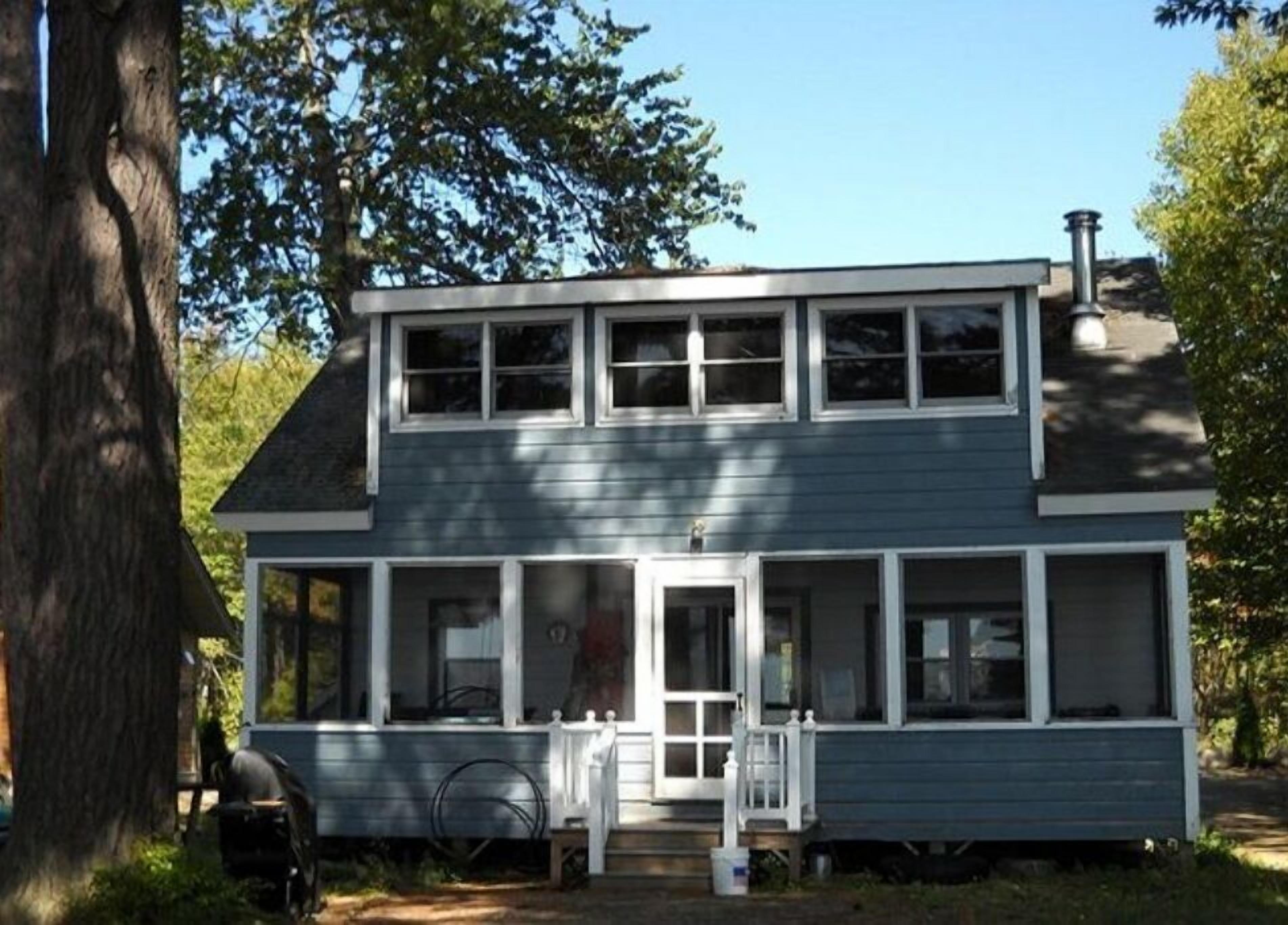 Une maison à deux étages avec un porche à l’avant, une cheminée et un garage.