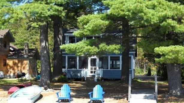 A cabin with a dock, two blue Adirondack chairs, and a boat on the shore. - Sandy Beach Cottage! (Belgrade)