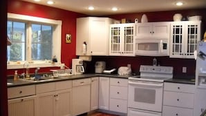 Une cuisine avec des meubles blancs, une cuisinière et un four à micro-ondes.