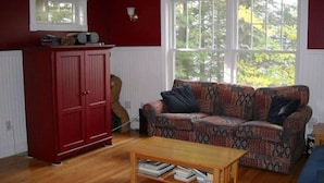 Un salon avec un meuble rouge, un canapé à motifs et une table basse en bois.
