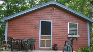 A small wooden house with a porch, two green plastic chairs, a table, and a dog. - Gramp's Camp (Belgrade)