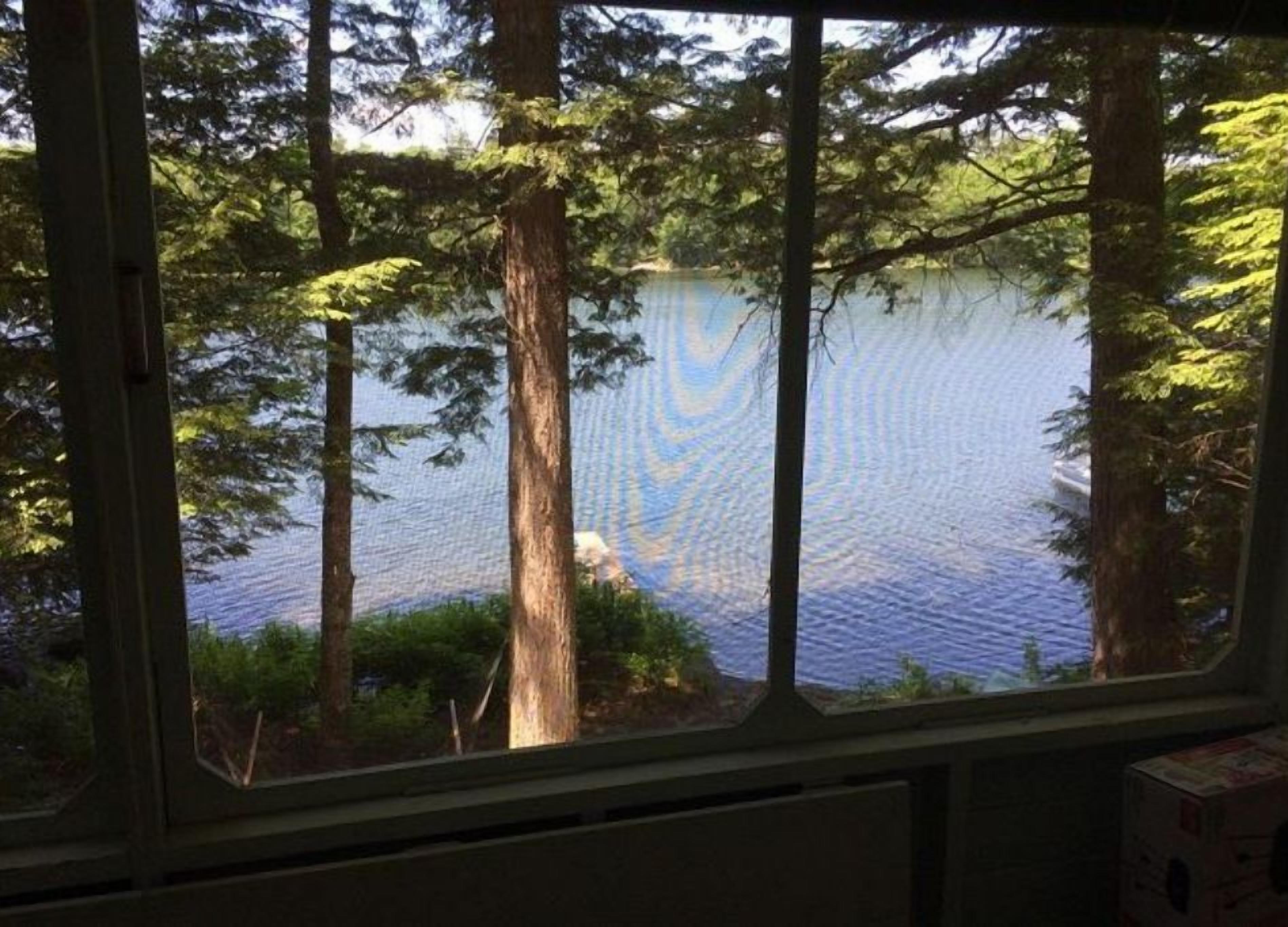 A view through a window of a lake surrounded by trees.