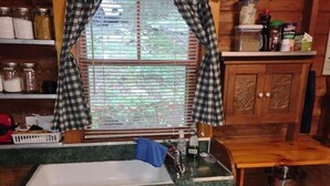 A kitchen with a window, wooden cabinets, and a sink. - Mystic Bungalow (Belgrade)