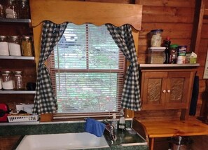 Kitchen area with sink, shelves, and cabinet.