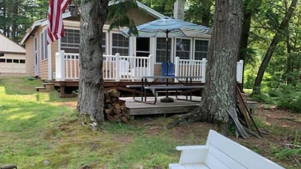 A cabin with a deck, a covered outdoor seating area, and a grill. - Hidden Cove Camp (Oakland)