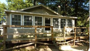 A wooden cabin with a porch and multiple windows. - Hidden Cove Camp (Oakland)