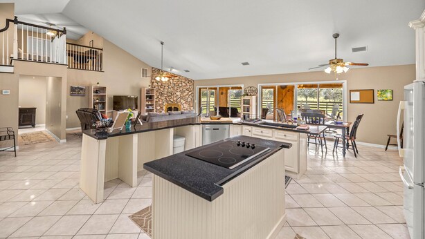 A spacious kitchen with a central island, a dining area with a table and chairs, and a staircase leading to an upper level. - Peaceful Private Ranch  Fire Pit  Near WEC, HITS, Rainbow Springs & Devil’s Den (Morriston)