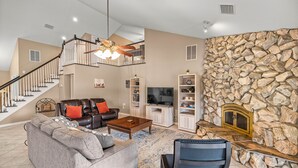A spacious living room with a staircase, a stone accent wall, a fireplace, and a television. - Peaceful Private Ranch  Fire Pit  Near WEC, HITS, Rainbow Springs & Devil’s Den (Morriston)