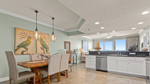 A spacious kitchen with a dining area, featuring a large island, white cabinetry, and a view to the outside. - Gulf-front condo w/ pool, hot tub and beach access (Panama City Beach)