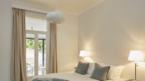 Ein Schlafzimmer mit einem Bett, zwei Nachttischlampen, einem Fenster mit Vorhängen und einer Pendelleuchte.