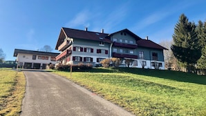 A large two-story house with a sloped roof, multiple windows, and a visible chimney.