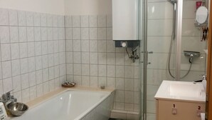 A modern bathroom with a freestanding bathtub, a glass-enclosed shower, and a vanity with a mirror.