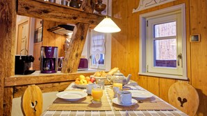 A breakfast table with plates, cups, and a coffee maker.
