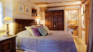 A bedroom with a large bed, wooden headboard, and a wooden wardrobe.