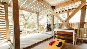 A wooden deck with a hammock, a table with benches, and a yellow board game.