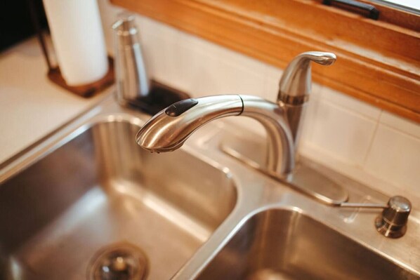 A stainless steel kitchen sink with a modern faucet. - Classic Duck Cottage – Heated Pool + Walk to Beach (Duck)