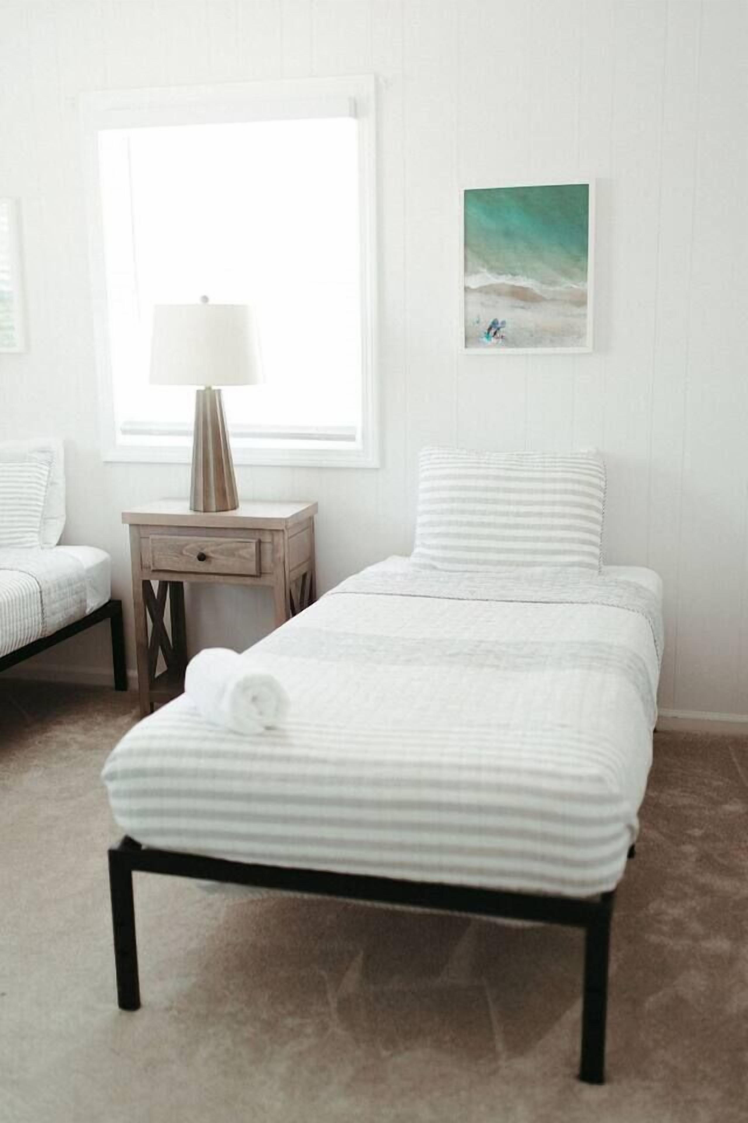 A bedroom with a bed, a nightstand, a lamp, and a wall art piece.