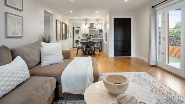 A modern living room with a sofa, a coffee table, and a dining area with a table and chairs. - PB Dream HOUSE Steps to Beach Bay ❤️Modern Private (San Diego)