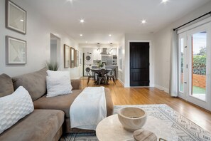 A modern living room with a sofa, a coffee table, and a dining area with a table and chairs.
