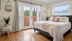 A bedroom with a bed, a window, a door, and a plant. - PB Dream HOUSE Steps to Beach Bay ❤️Modern Private (San Diego)