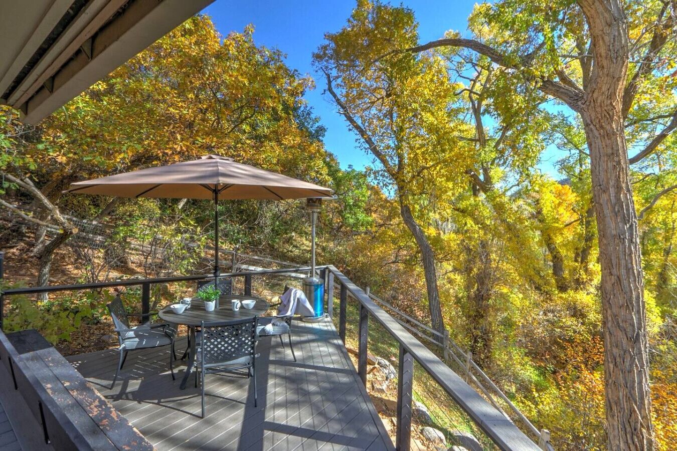 Une terrasse en bois avec des meubles d’extérieur, une table et un parasol.