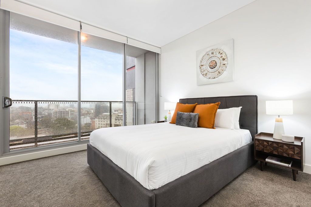 Un dormitorio moderno con una cama grande, vistas a la ciudad y un adorno en la pared.