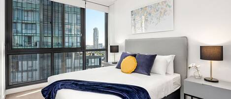 A modern bedroom with a large bed, a city view, and a minimalist design.