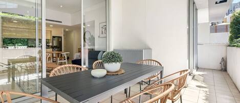 A modern dining area with a dark table, wicker chairs, and a potted plant.