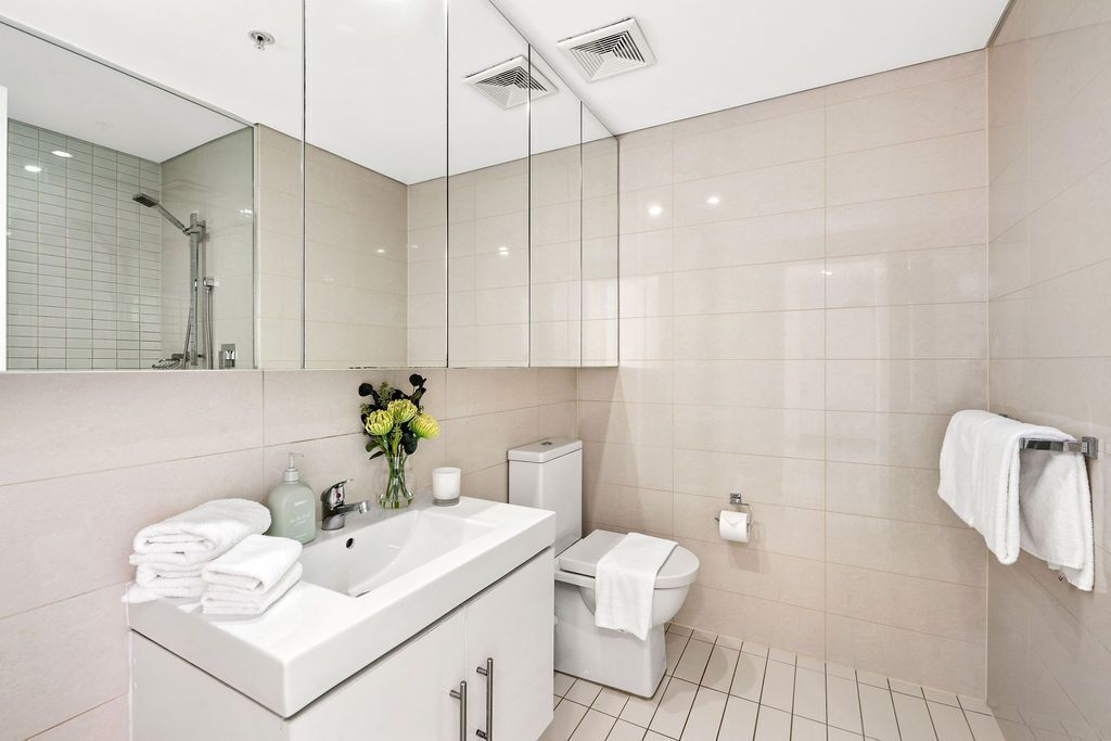 A modern bathroom with a large mirror, white sink, and toilet.