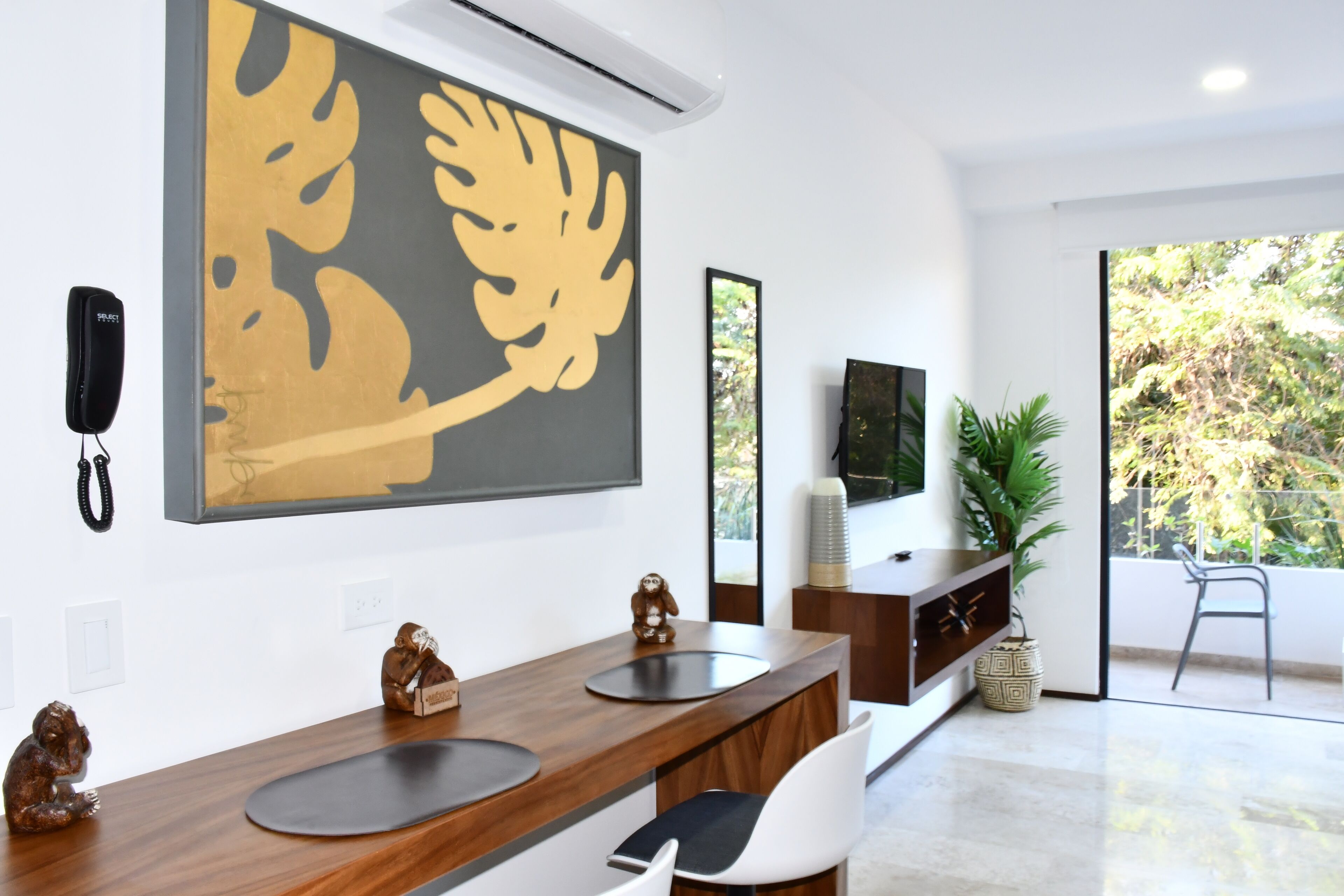 A modern kitchen with a wooden countertop, a large abstract painting, a telephone, and a television.