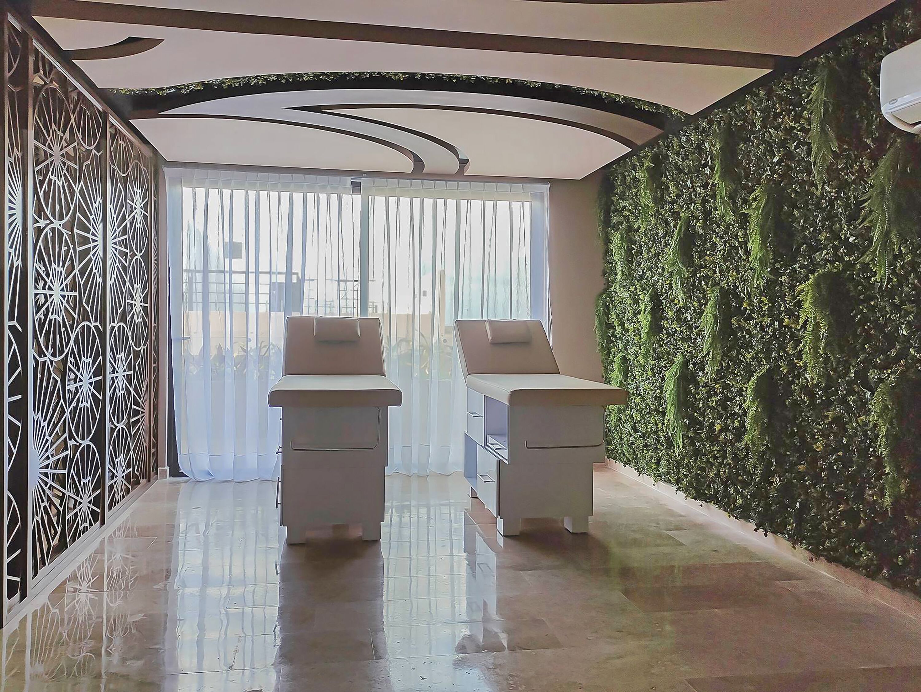 A modern room with two white chairs, a glass door, a green wall, and a decorative metal partition.