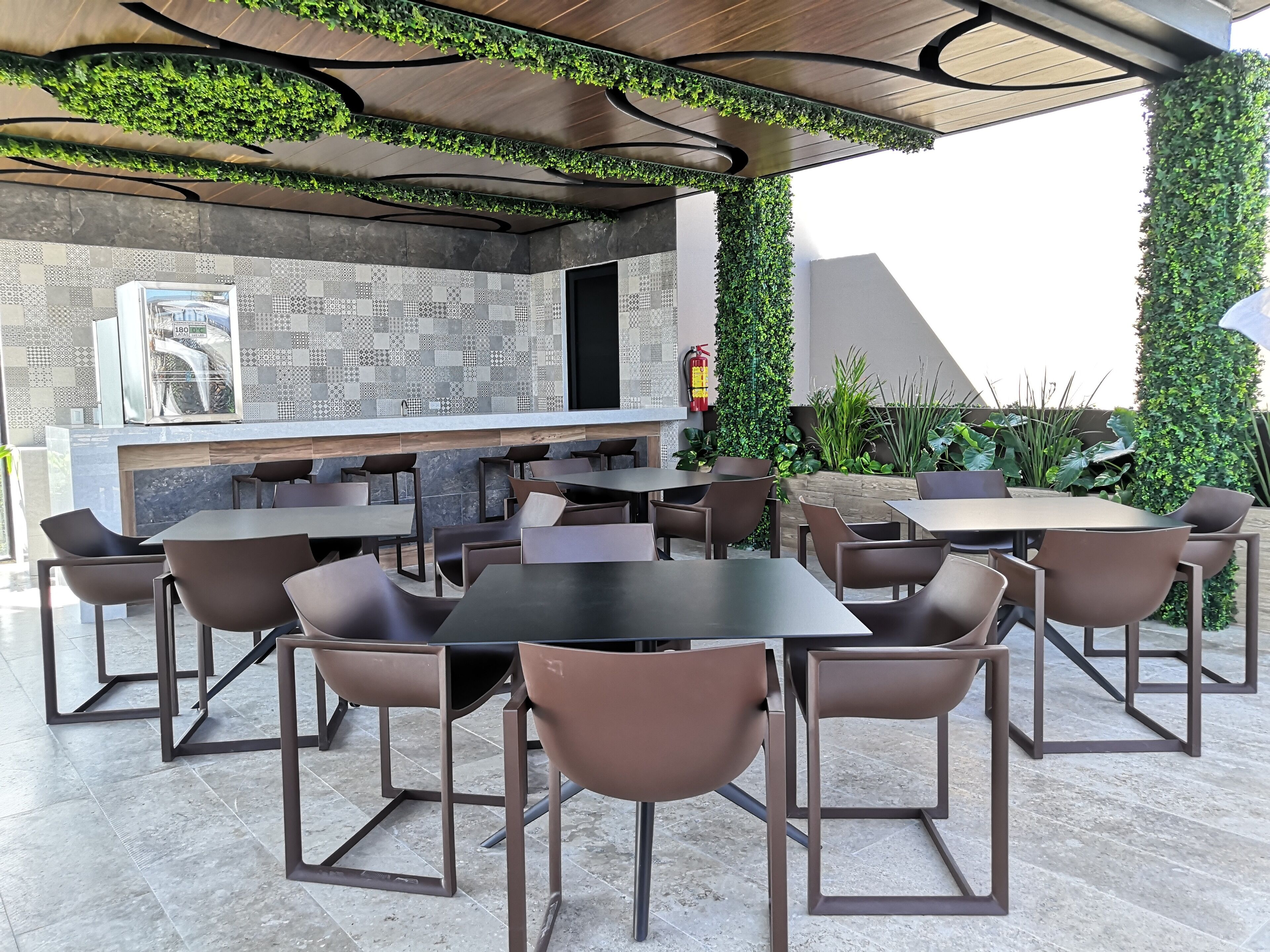 An outdoor dining area with modern furniture and a decorative wall with patterned tiles.