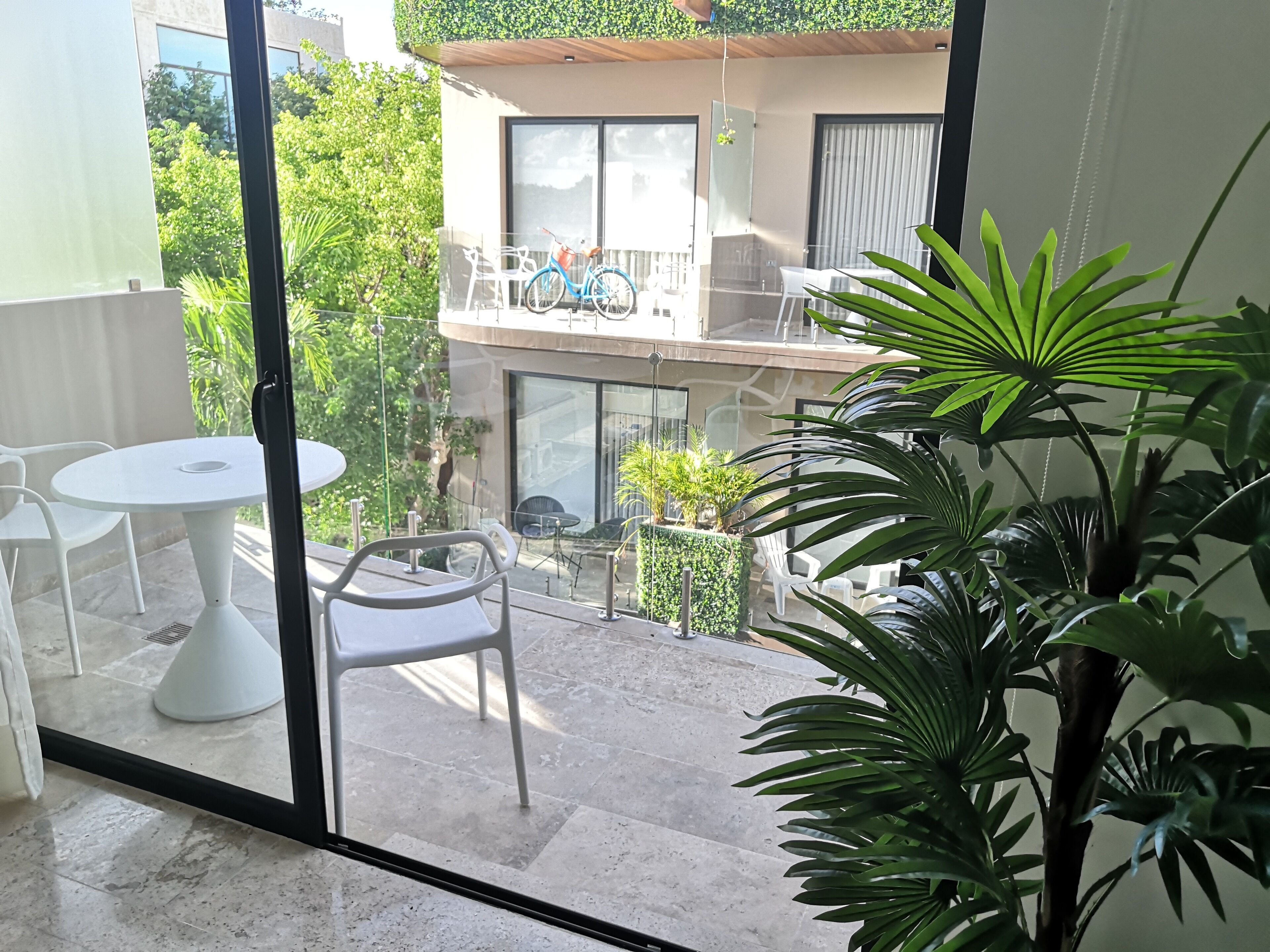A balcony with a table and chairs, a bicycle, and a potted plant.