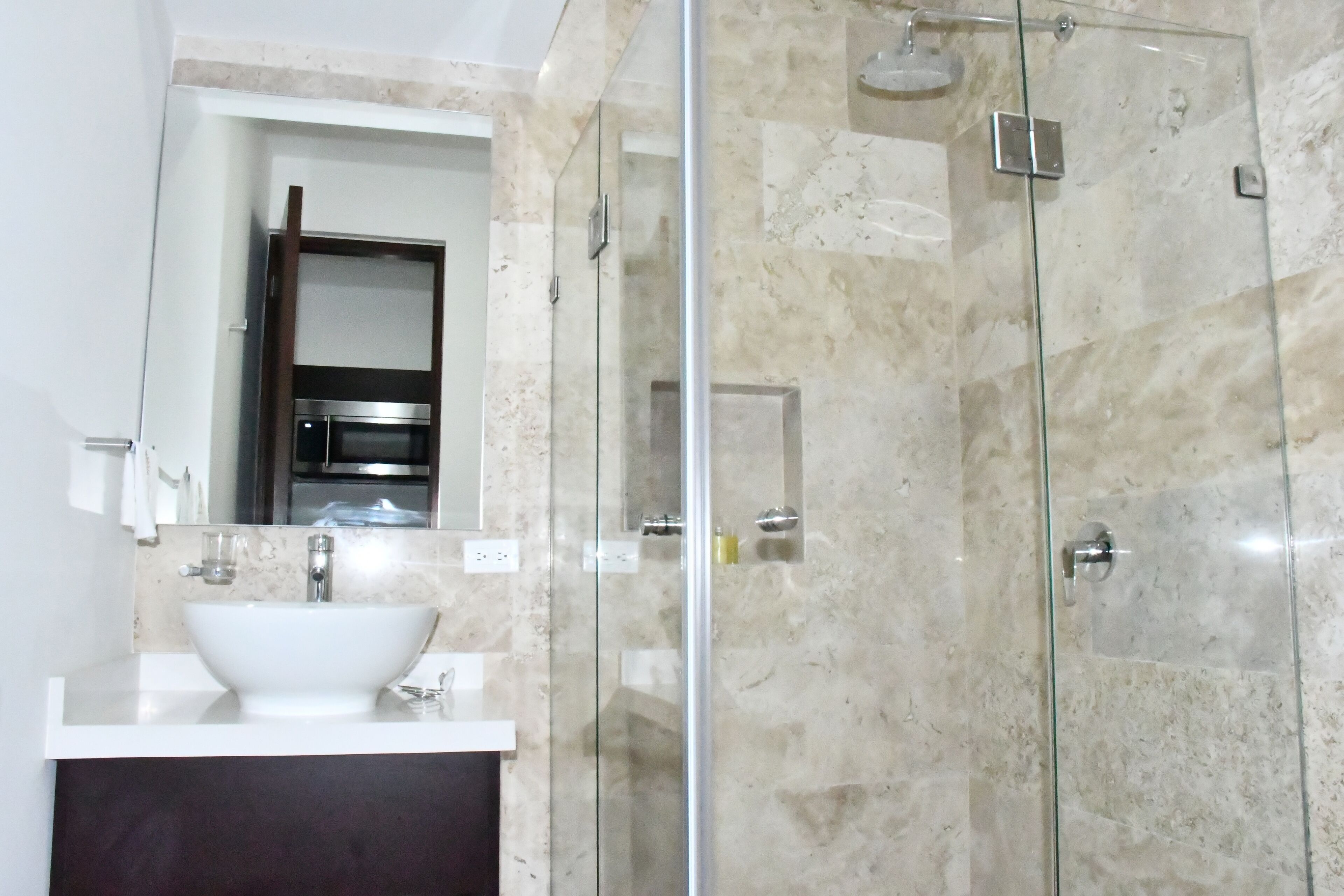 Un bagno moderno con doccia vetrata, un lavandino bianco e uno schienale in marmo.