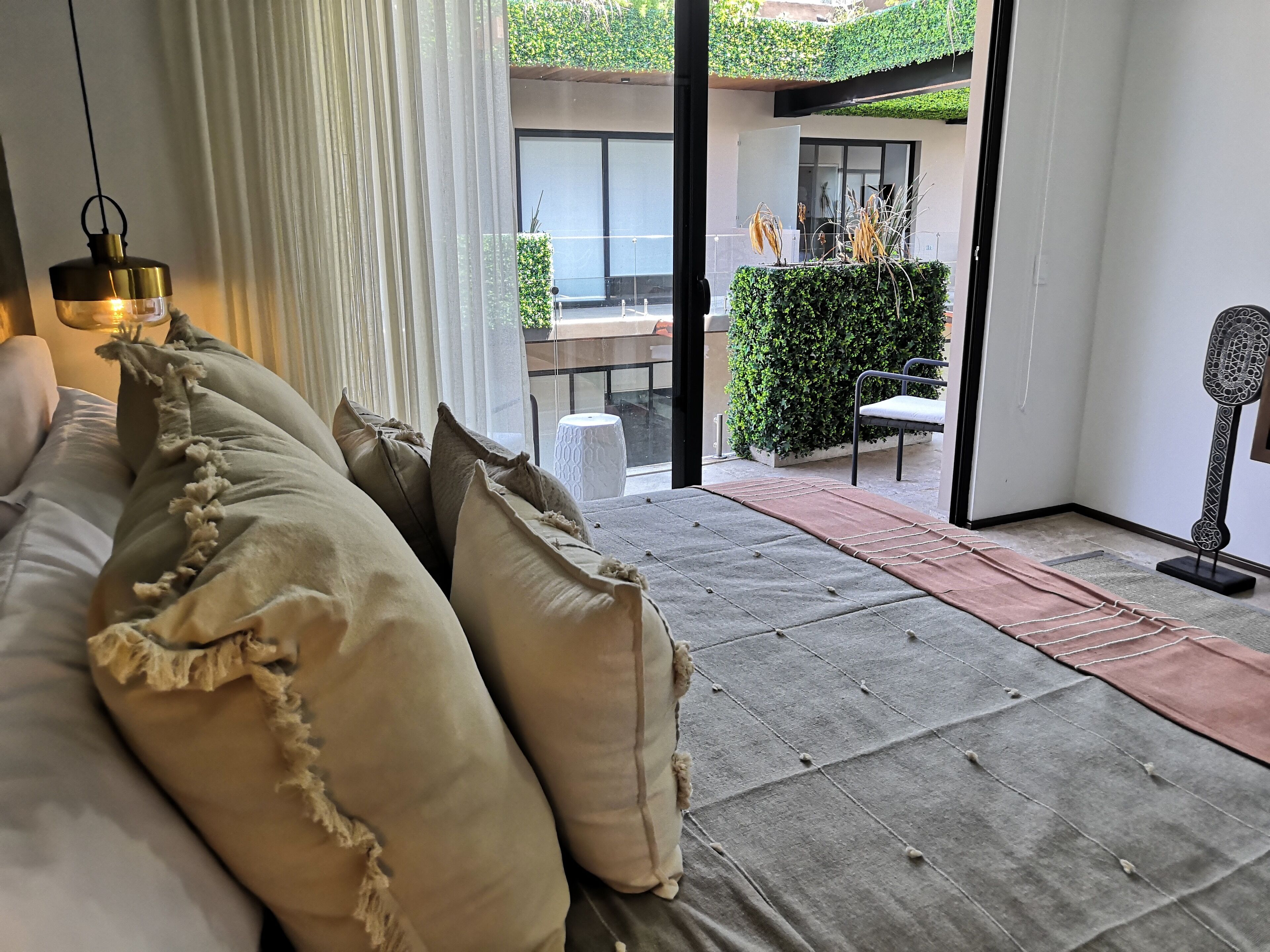 A modern living room with a sofa, a hanging light fixture, and a view of the outdoor patio area.