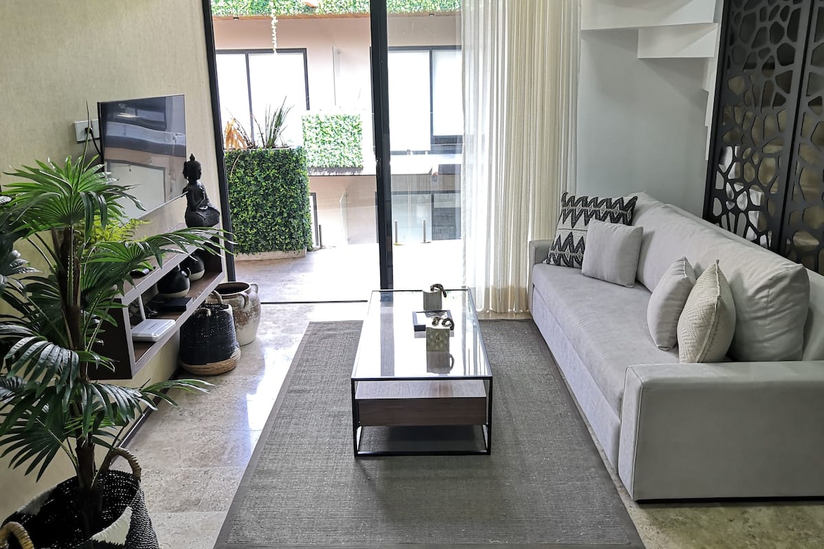 A modern living room with a sofa, coffee table, and potted plants.