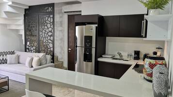 Una cocina moderna con refrigerador empotrado, una encimera blanca y un área de comedor con dos sillas.