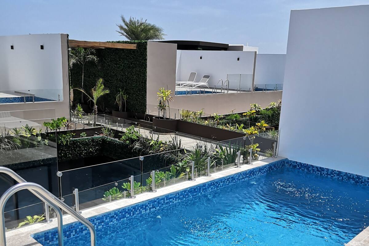 A rectangular swimming pool with clear blue water, surrounded by a tiled deck.