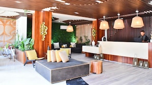 A modern reception area with a wooden reception desk, a sofa with cushions, and a bicycle in the background. - Menesse Tulum by Spot Rentals (Tulum)