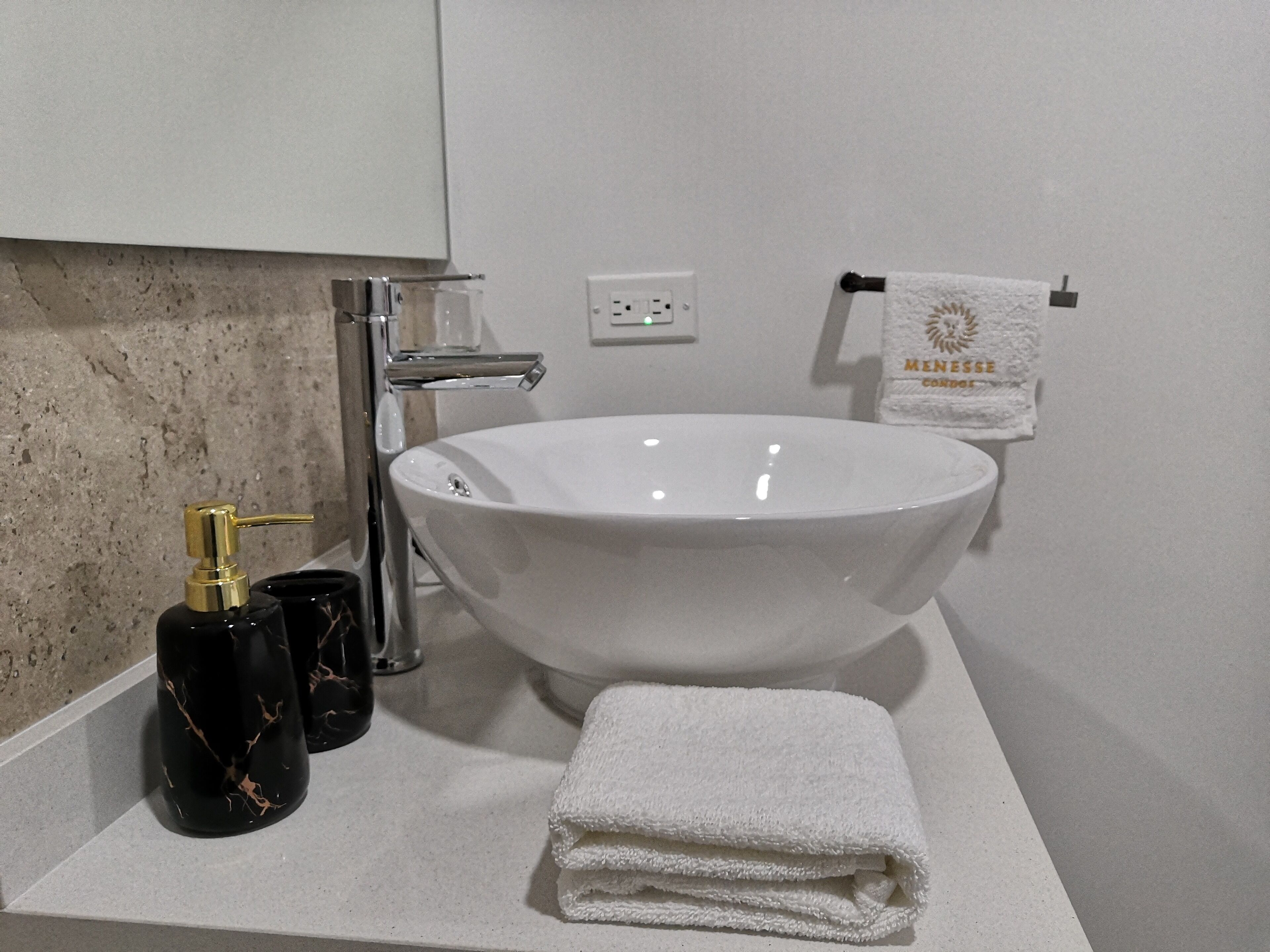 A bathroom with a white sink, a towel, and a bottle of soap.