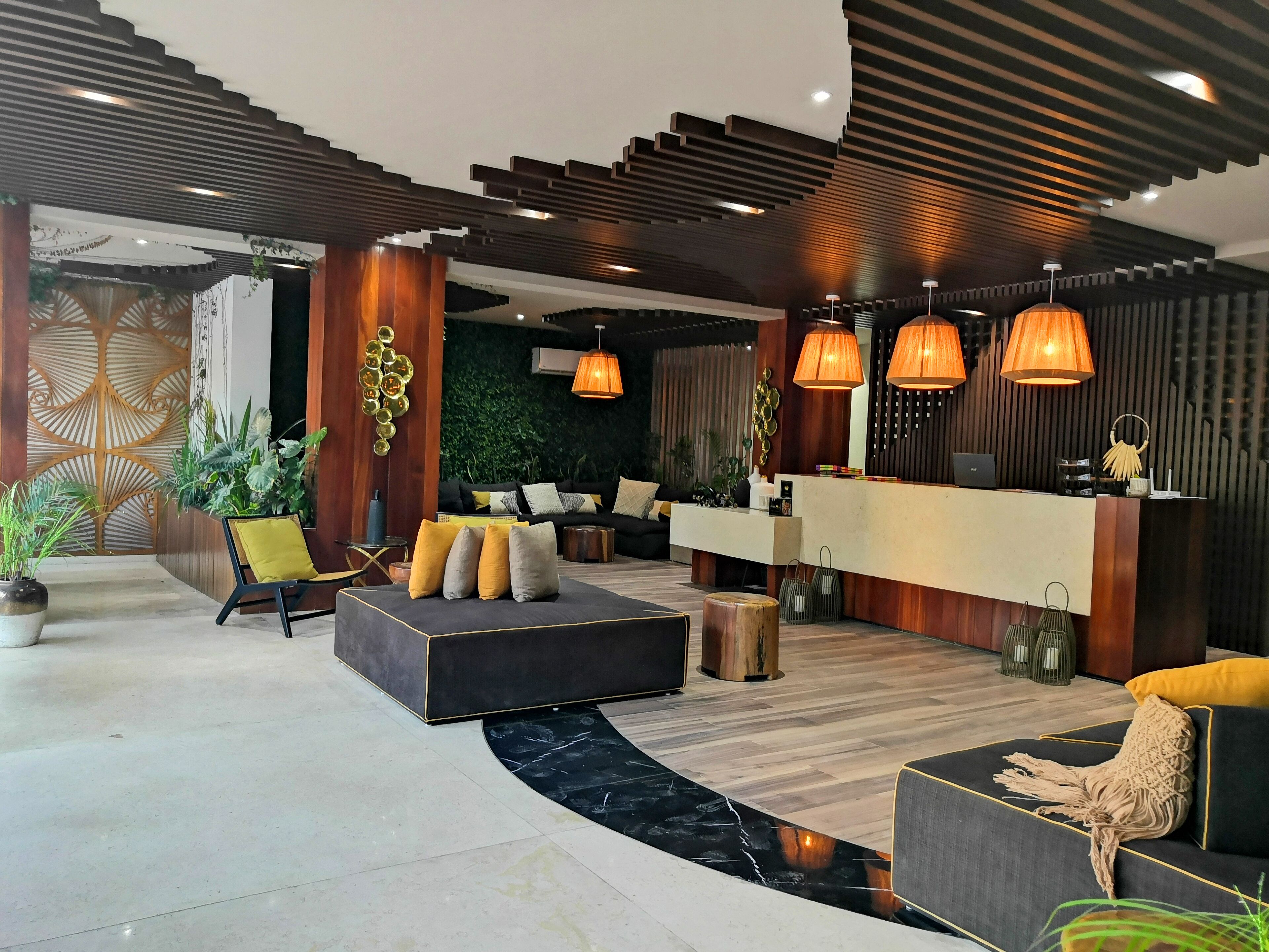 A modern lobby with a reception desk, seating area, and decorative plants.