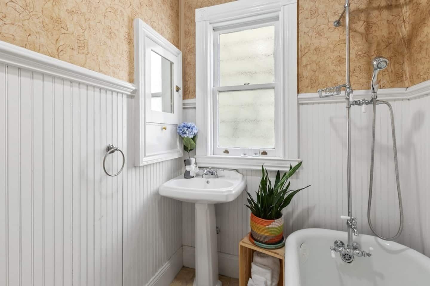 A bathroom with a white sink, mirror, and bathtub.