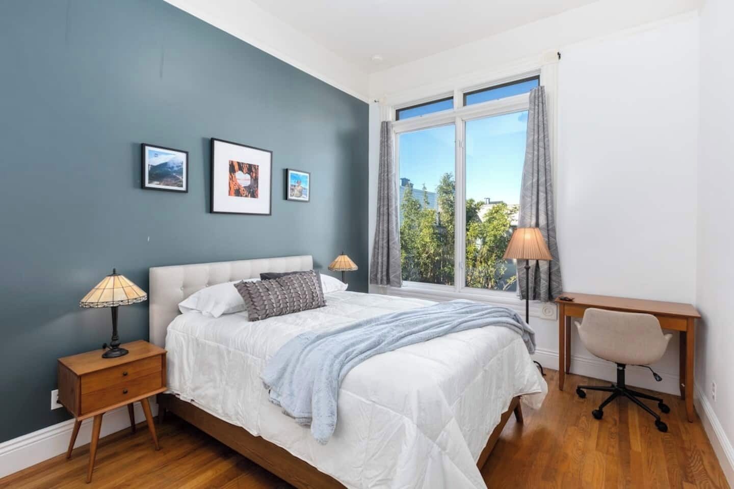 A bedroom with a bed, bedside tables, a desk, and a chair.