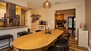 Une cuisine moderne avec une grande table à manger en bois, des appareils électroménagers intégrés et un luminaire suspendu.