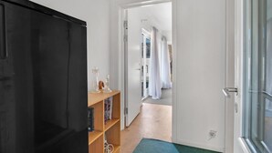 Een gang met een houten boekenkast, een zwarte deur en een witte deur die naar een badkamer leidt.