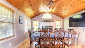 A dining area with a wooden ceiling, a large table, and matching chairs.