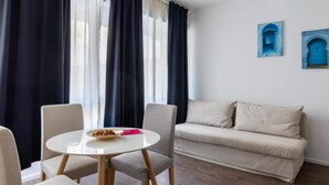 A room with a round table, two chairs, a sofa, and a window with curtains. - Largo Molina Studio III by Wonderful Italy (Bologna)