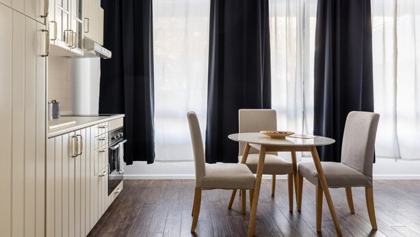 A modern kitchen with white cabinets, a built-in oven, and a dining area with a round table and four chairs. - Largo Molina Studio III by Wonderful Italy (Bologna)