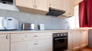A modern kitchen with wooden cabinets, a built-in oven, a toaster, and a kettle.